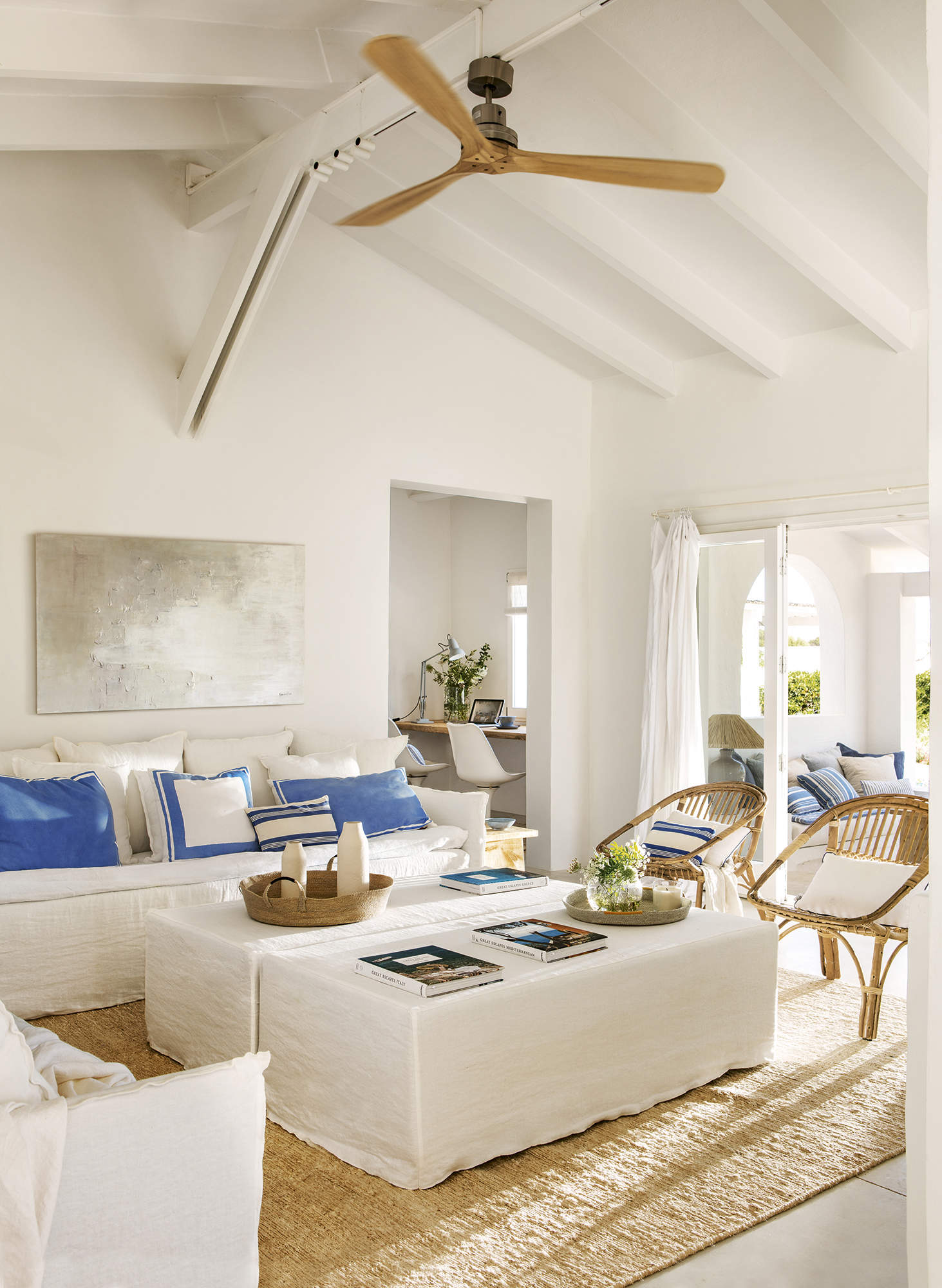 Salón mediterráneo con sofá de lino blanco, pufs, cojines azules y sillones de fibras
